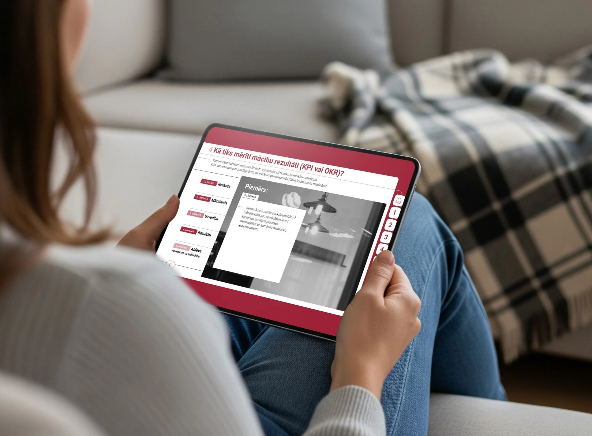 Woman holding a tablet displaying a lesson about measuring learning outcomes with KPIs or OKRs.
