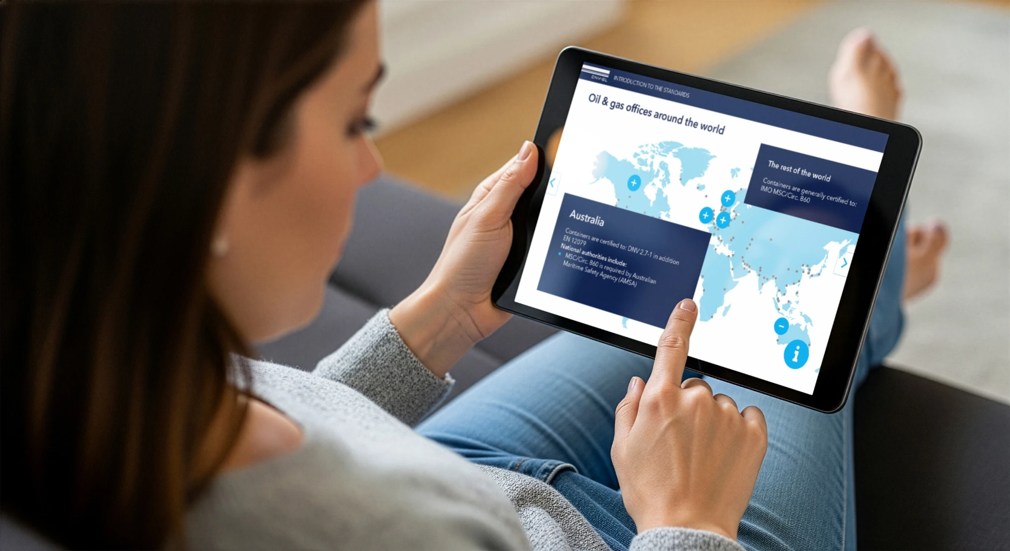Woman using a tablet displaying a world map of oil and gas offices.