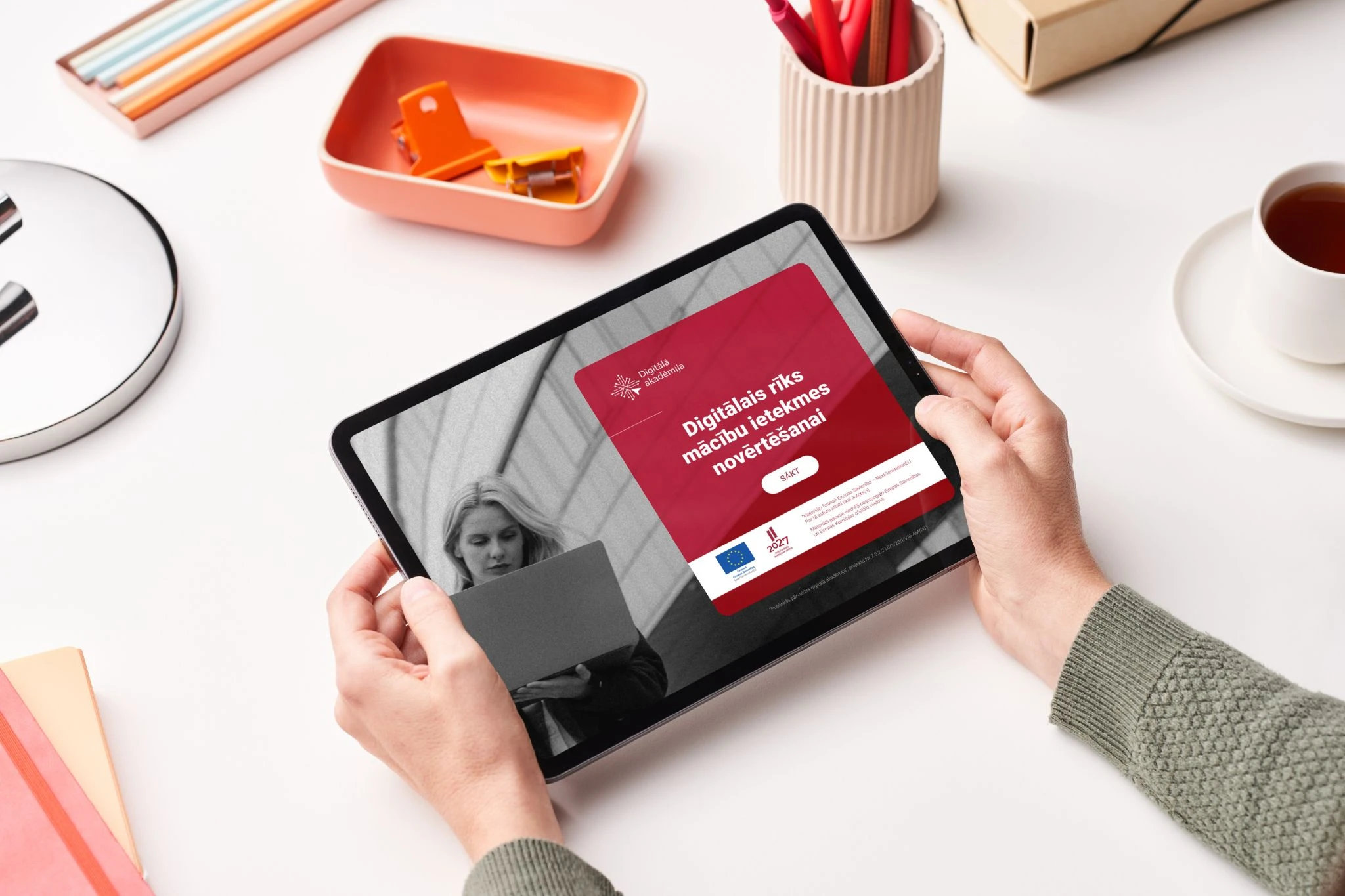Person holding a tablet displaying a Latvian digital skills training course.