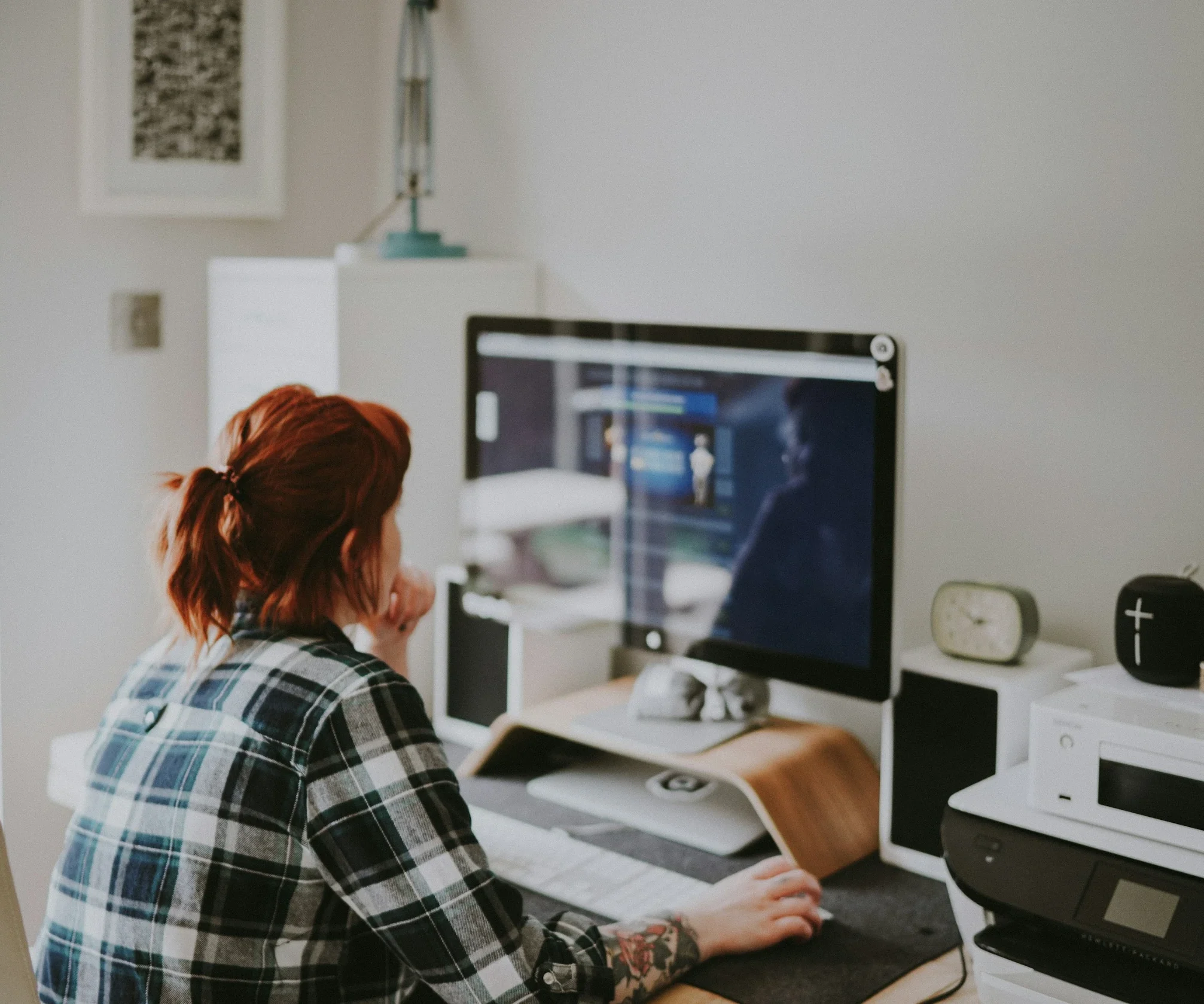 Woman working at a desktop computer in a home office.